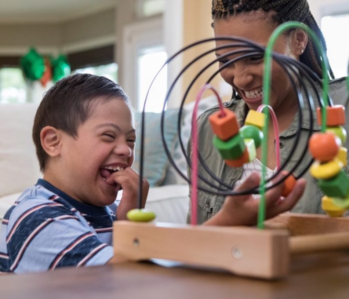 When the mid adult mom and her special needs son play in the living room, they laugh together.